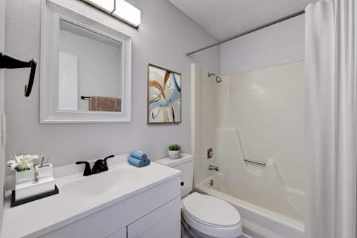 A white bathroom with a white toilet, sink, and bathtub at The Hampton Meadows Apartments,Des Moines, Iowa