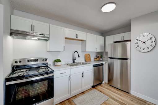 A modern kitchen with a stove, sink, and refrigerator at The Hampton Meadows Apartments, Des Moines, IA