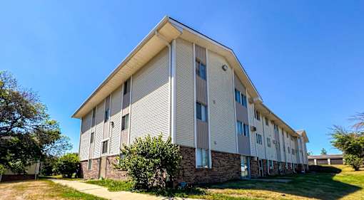 A modern apartment building with a clear blue sky above at The Ridges Apartments, Iowa