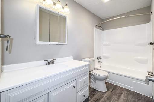 A white bathroom with a toilet, sink, and bathtub at The Ridges Apartments, Iowa