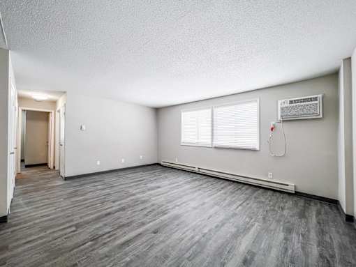 A room with a grey floor and a window with blinds at The Ridges Apartments, Iowa