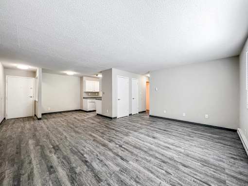 A spacious room with grey flooring and white walls at The Ridges Apartments, Des Moines