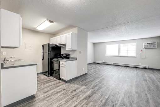 A kitchen with white cabinets and a black refrigerator at The Ridges Apartments, Des Moines, Iowa