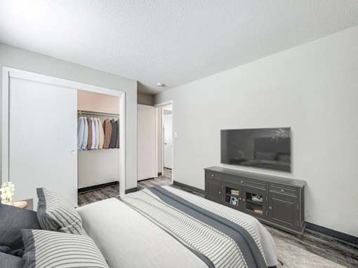 A bedroom with a bed, a wardrobe, and a television at The Ridges Apartments, Iowa, 50315