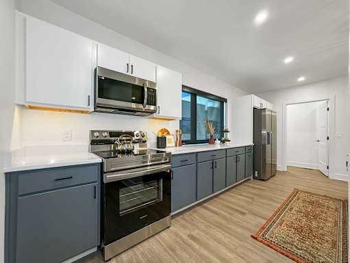 a kitchen with blue cabinets and a stove and a microwave at Matilda 235 Townhomes, Des Moines, IA