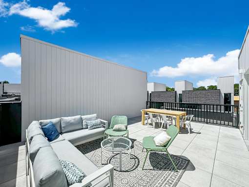 a rooftop patio with a couch and chairs and a table at Matilda 235 Townhomes, Des Moines, IA
