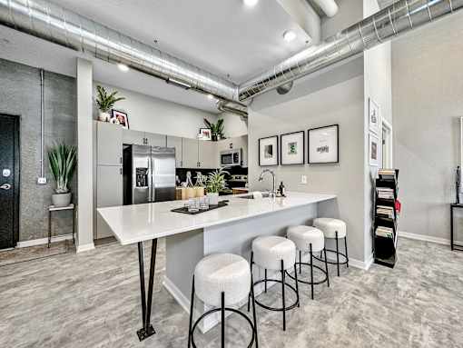 A kitchen with a white counter and bar stools.at Level, Des Moines Iowa   