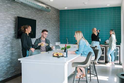 A group of people are gathered around a kitchen island.at Level, Des Moines, 50309  