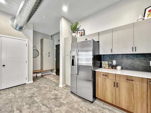 A kitchen with a stainless steel refrigerator and wooden cabinets.at Level, Des Moines Iowa   