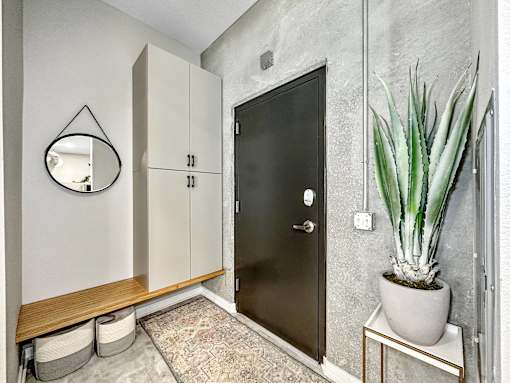 A black door is in a white room with a plant on a side table.at Level, Iowa, 50309