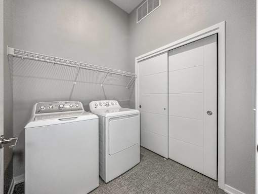 A laundry room with a washer and dryer and a white closet.at Level, Des Moines, IA  