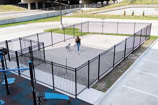 A woman walking a dog in a fenced area.at Level, Des Moines  