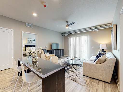 a living room and dining room with a glass table at Linc, Des Moines, IA 50309  