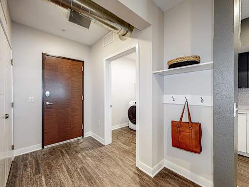 a hallway with a door to a bathroom and a bag on the wall at Linc, Iowa, 50309
