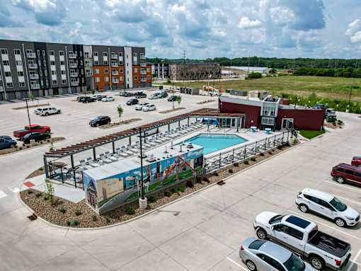 an aerial view of a parking lot with a pool and a building at Linc, Des Moines, IA  