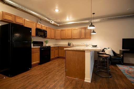 a kitchen with an island and a black refrigerator at Melbourne Apartments, Des Moines, IA,  50320