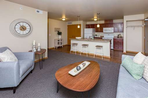 a living room with a couch and a table in front of a kitchen at Melbourne Apartments, Des Moines, IA,  50320