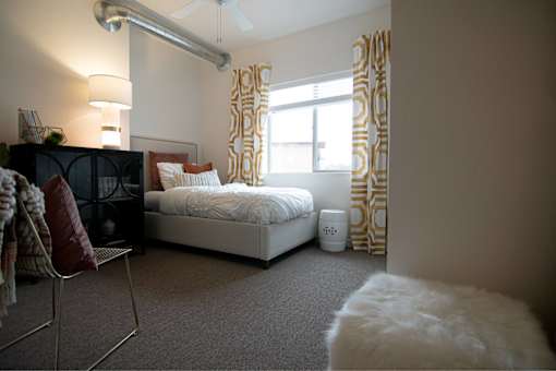 a bedroom with a bed and a window with curtains at Melbourne Apartments, Des Moines, IA