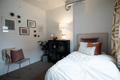 a bedroom with a bed and a lamp and pictures on the wall at Melbourne Apartments, Des Moines, Iowa