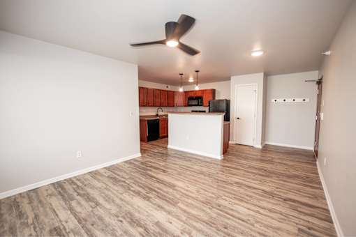 an empty living room with a kitchen and a ceiling fan at Meadowlark Place Apartments, Grimes