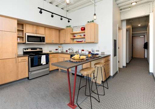 a kitchen with wooden cabinets and a table with stools at Eagle View Lofts, Des Moines, 50309