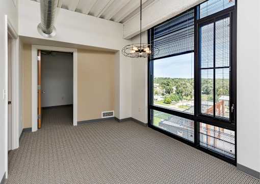 an empty living room with large windows and a door to a balcony at Eagle View Lofts, Des Moines, Iowa