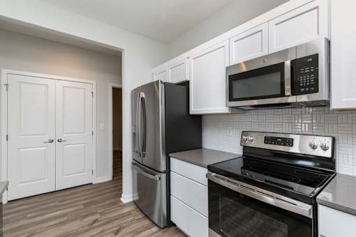 A kitchen with black appliances and white cabinets. at Two Rivers Home Rentals, West Des Moines, IA