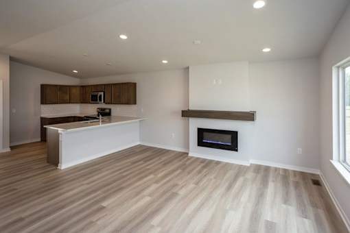 an empty living room with a fireplace and a kitchen at Two Rivers Home Rentals, West Des Moines