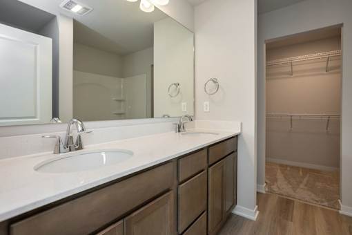 A bathroom with a sink, mirror, and wooden cabinets. at Two Rivers Home Rentals, Iowa 50266