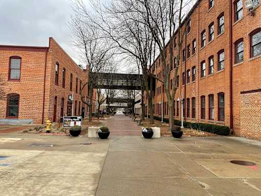 A long brick building with a walkway in front.at Plant 1 Lofts, N. Newton, IA  