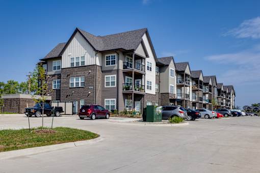 A row of townhouses with cars parked in front.