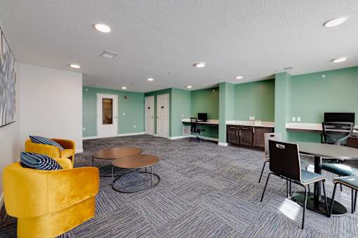 A room with a yellow chair and a grey carpet.