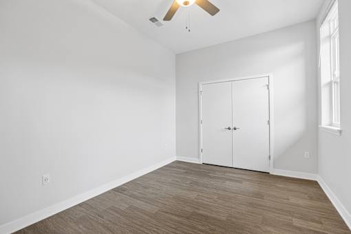 A room with a white wall and a wooden floor with a white closet.