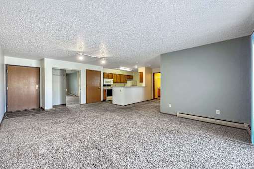 the living room and kitchen of an apartment with a carpeted floor at Autumn Park, Sioux Falls  