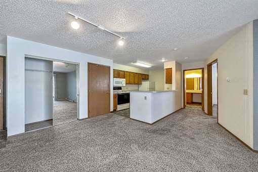 an empty living room and kitchen with a refrigerator and a sink at Autumn Park, Sioux Falls South Dakota  