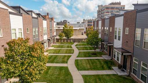 A view of a residential area with apartment buildings and a tree-lined walkway.