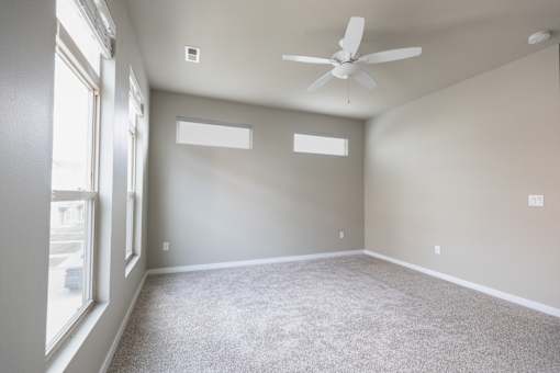 A room with a ceiling fan and carpeted floor.