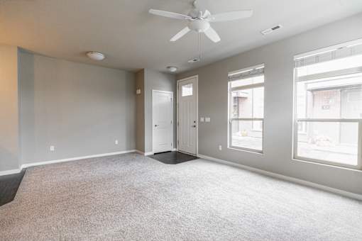 A spacious room with a ceiling fan and carpeted floor.