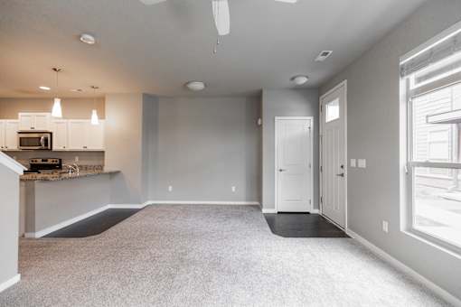 A spacious living room with a kitchen area in the background.