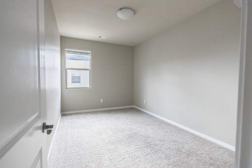 A room with a carpeted floor and a window.