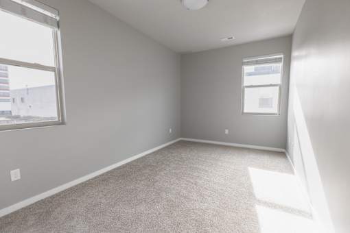 A room with a carpeted floor and a window letting in sunlight.