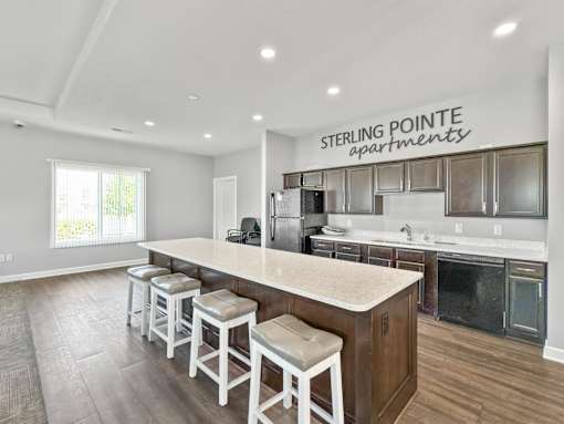 A kitchen with a bar area and stools in a Sterling Pointe Apartments.