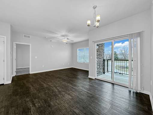 an empty living room with a sliding glass door to a balcony at Stonegate Crossing Apartments, Clive, IA