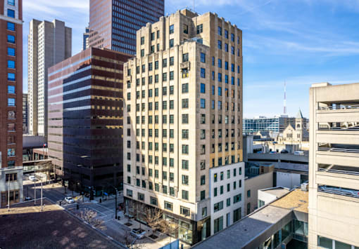 A tall building with many windows stands in the middle of a city.