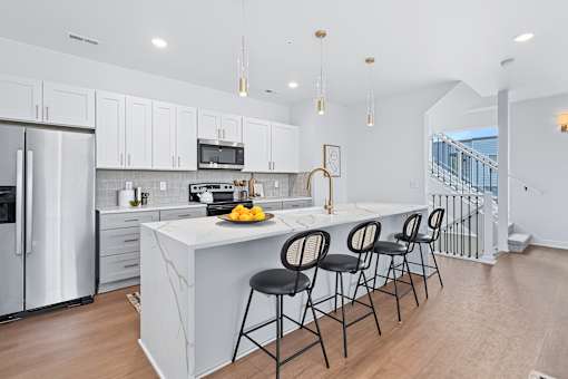 White kitchen island with pendant lighting and bar stools at The Flats at West Glen Apartments, West Des Moines, IA 50266