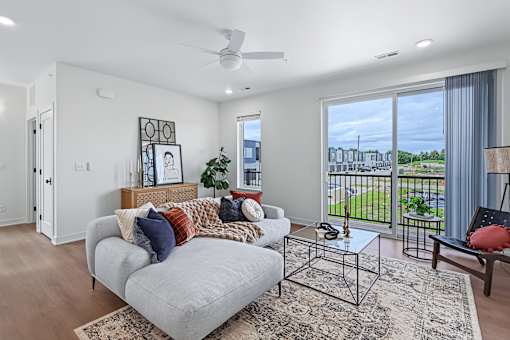 Modern living room with sectional and balcony view at The Flats at West Glen Apartments, West Des Moines, IA