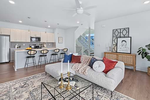 Open living space with gray sofa and ceiling fan at The Flats at West Glen Apartments, West Des Moines