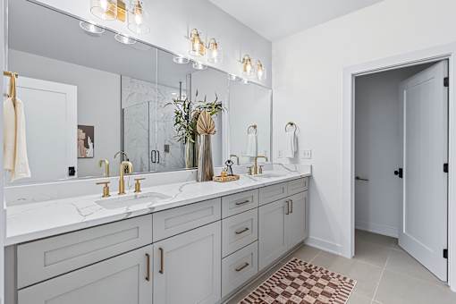 Master bathroom with double sink vanity and gold fixtures at The Flats at West Glen Apartments, Iowa