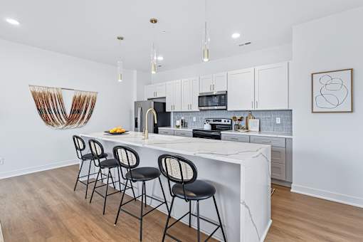 Kitchen island with marble countertop and four bar stools at The Flats at West Glen Apartments, West Des Moines, IA 50266