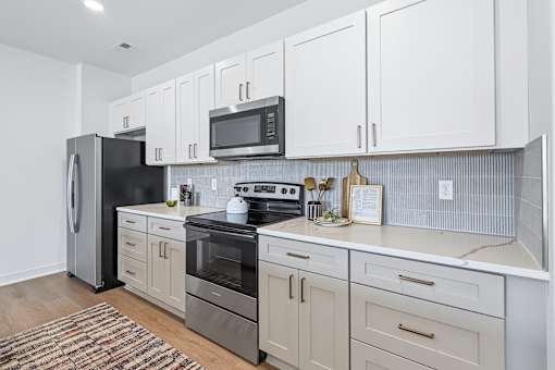 Galley kitchen with white cabinetry and corrugated backsplash at The Flats at West Glen Apartments, West Des Moines, IA